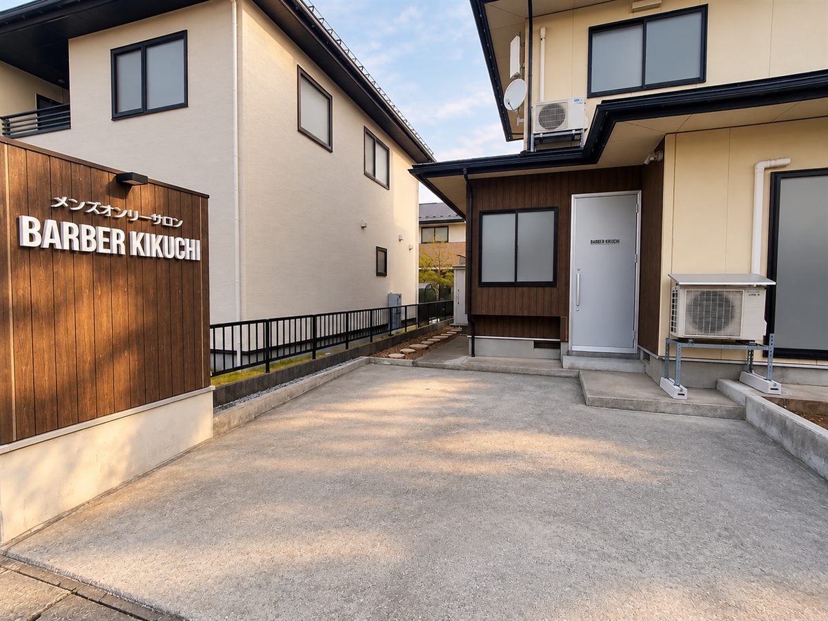店舗の外観。看板と入口の扉、扉の前の駐車場